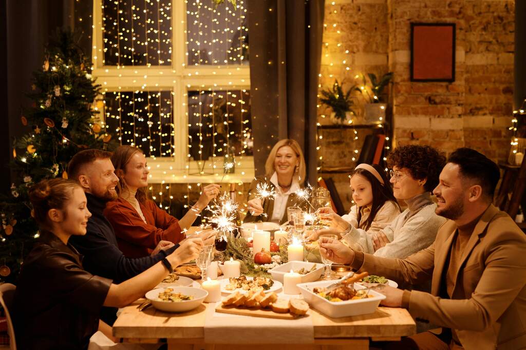 Ceia de natal: família reunida para a Ceia, muitas pessoas ao redor da mesa muita comida, e ao fundo uma janela toda enfeitada com piscas e uma mesa com uma ceia farta