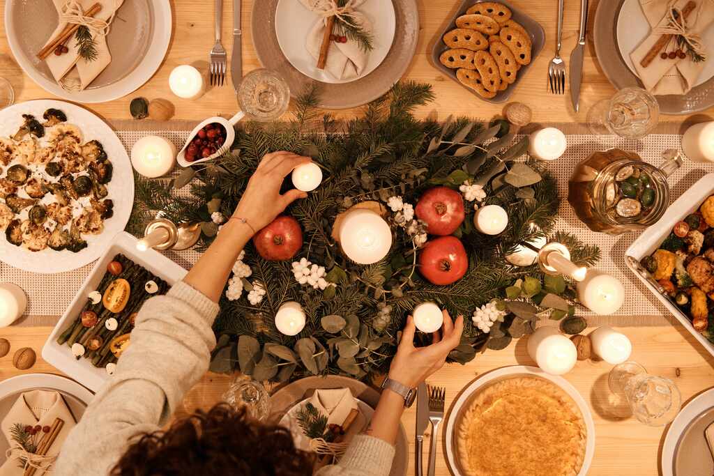 Festa-natalinal: Visão superior de uma mesa em momento da ceia, com luz de velas, maçãs e comida sobre a mesa