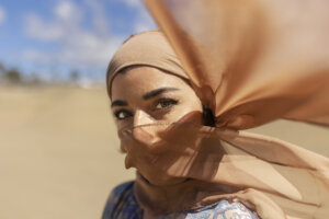 Mulheres no Oriente Médio: mulher usando uma burca que deixa apenas seus olhos expostos. No fundo da imagem aparece um deserto.
